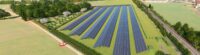 Drohnenbild auf einen Acker, mit Computersimulation einer Freiflächen-PV-Anlage.