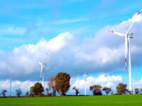 Der Windpark Lindtorf, im Hintergrund einige Bäume, große Wolken und blauer Himmel.