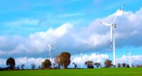Fortsetzung von Energiepartnerschaften Der Windpark Lindtorf, im Hintergrund einige Bäume, große Wolken und blauer Himmel.